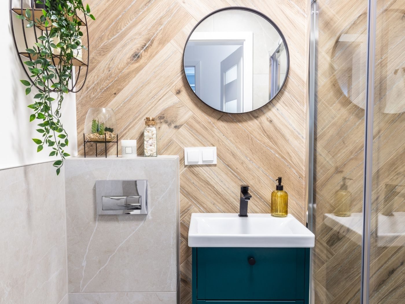 A compact en-suite with a wood-effect herringbone feature wall and a teal vanity unit