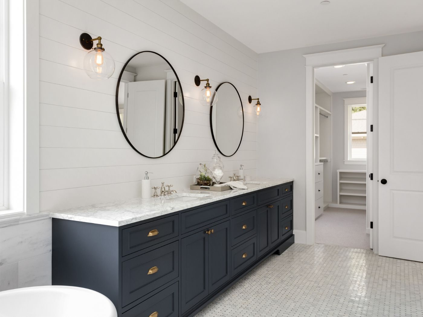 A long navy vanity unit with a marble worktop, twin basins and brass cup handles