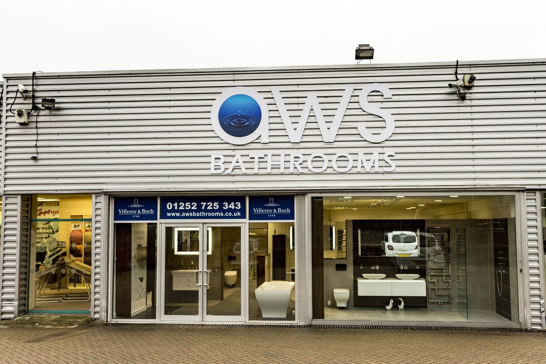 The AWS Bathrooms shopfront in Farnham with display bathrooms visible through the glazing